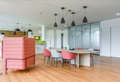 Breakout area with a large communal table, colorful chairs, and a pink privacy booth.