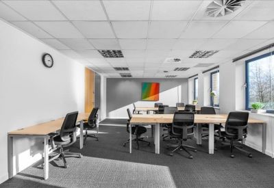 Bright open-plan workspace with wooden desks and a colorful rainbow feature wall.