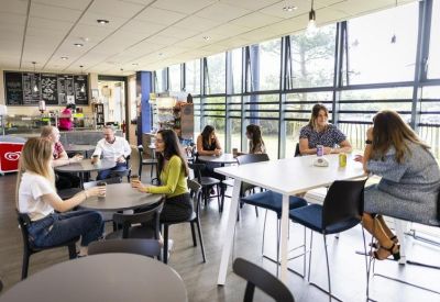 Spacious on-site cafe with modern seating, large windows, and people socializing.