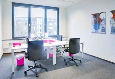 Modern office suite with four desks, ergonomic black chairs, and bright pink accents.