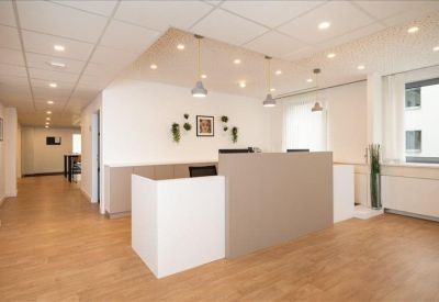 Minimalist reception desk area with warm wood flooring and recessed ceiling lighting.
