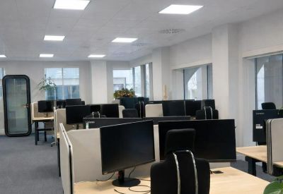 Modern office suite with sit-stand desks and natural light from large windows.