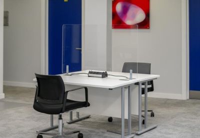 Professional meeting desk with a clear glass partition and black chairs.