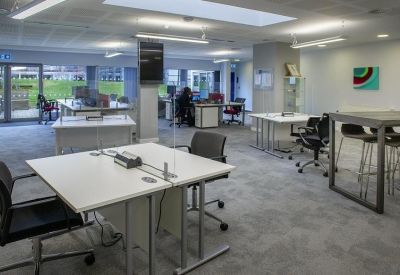 Expansive open-plan workspace with multiple desk clusters and natural light.