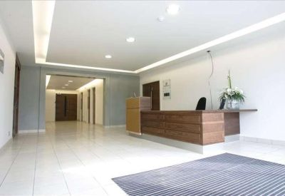 Bright reception area featuring a wooden front desk and polished tile flooring.