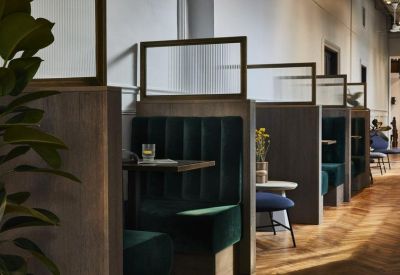 Individual working booths with dark green velvet seating and glass partitions.
