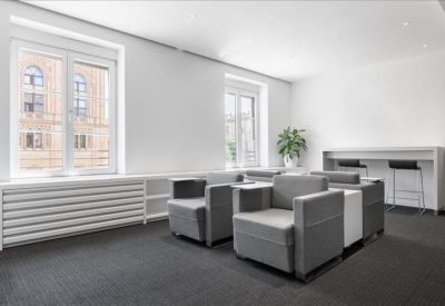 Minimalist lounge area with grey upholstered armchairs and a high breakfast bar.