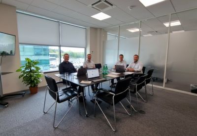 Contemporary meeting room with a large screen, glass walls, and a conference table seating six.