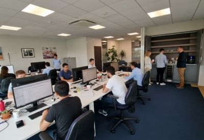 Lively office breakout area with a built-in coffee station and team members socialising.