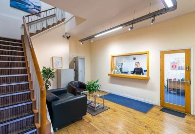 Reception area featuring a wooden staircase, black leather seating, and a staffed service window.