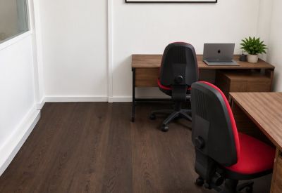 Private office featuring dark wood flooring, two desks with red chairs, and a landscape wall art piece.