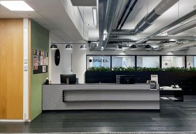 Sleek grey reception desk in a lobby with industrial exposed pipe ceilings.