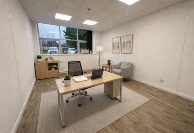 Bright private office suite with a wooden desk, grey armchair, and large window.