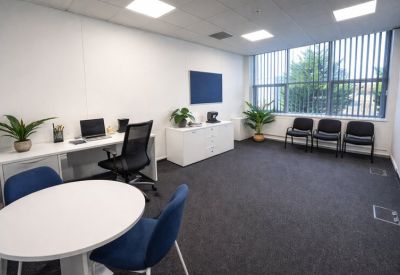 Meeting room with a round white table, blue chairs, and black-out blinds.