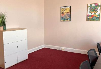 Bright office space with red carpeting, white storage lockers, and framed wall art.