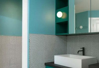 Modern bathroom with vibrant teal walls, white vessel sink, and penny tile splashback.