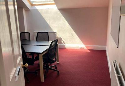 View through a doorway into a private office with red carpet and a skylight window.