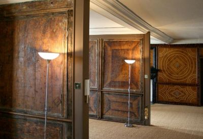Spacious room with ornate wood-paneled walls and floor lamps.