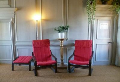 Bright waiting area featuring two red armchairs and wall paneling.