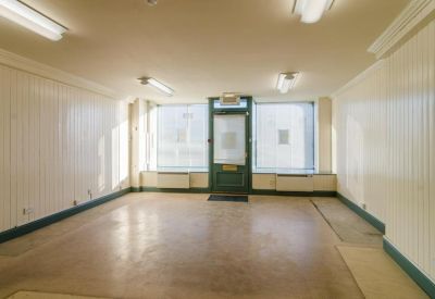 Empty office suite with white wood-paneled walls and large windows.