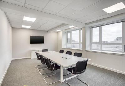 Contemporary meeting room with a long white table, black chairs, and large windows for natural light.