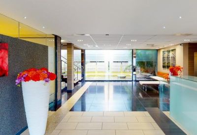 Modern lobby with a white flower vase, dark stone flooring, and a sleek reception desk.