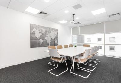 Modern conference room with a large white table and a world map mural on the wall.
