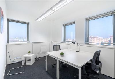Private office space with two desks, ergonomic chairs, and large windows providing natural light.