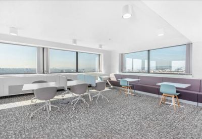 Bright communal lounge and breakout area featuring a long table and light blue chairs.