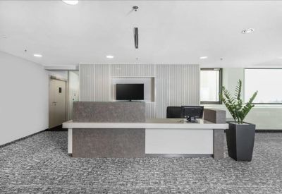 Modern minimalist reception desk with grey stone finish and a potted plant.