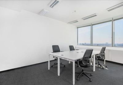 Bright private office featuring a white desk, ergonomic black chairs, and large windows.