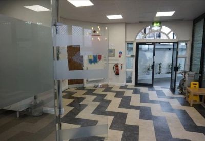 Spacious entrance area featuring a striking chevron-patterned floor and glass partitions.