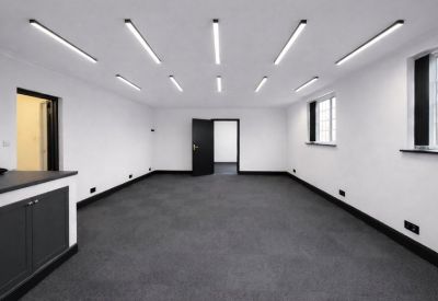 Large open-plan room with grey carpet, dark doors, and integrated kitchen cabinetry.