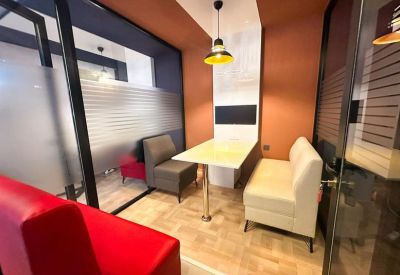 Breakout booth with white and grey banquette seating and a yellow pendant light.