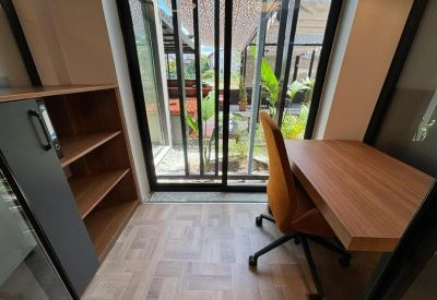 Private office pod with a wooden desk, orange chair, and large glass window view.