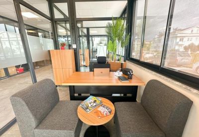 Quiet meeting area with grey seating and a small round side table next to large windows.