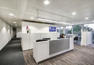Clean, professional reception area with a white front desk and dark carpeted hallway.