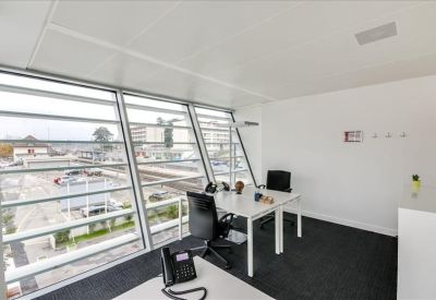 Private office with two desks and large windows overlooking the city.