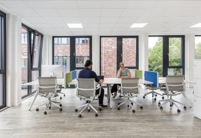 Open-plan office with multiple workstations and colorful acoustic dividers.