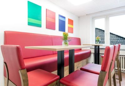 Bright break area featuring red cushioned bench seating and colorful wall art.
