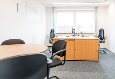Private office suite with a wooden desk and black ergonomic chairs.