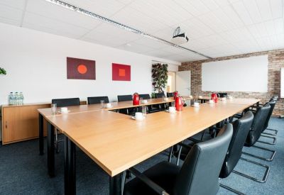 Large U-shaped meeting table with black chairs and red accents.