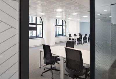 Open-plan workspace with multiple desks and black chairs.