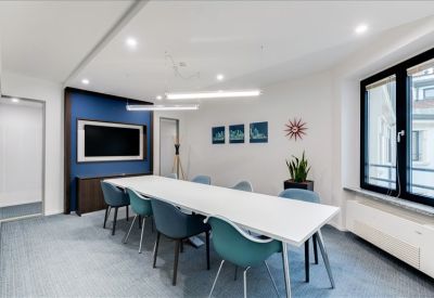Modern conference room with a blue feature wall, long white table, and teal chairs.