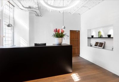 Minimalist reception area with a dark desk and wood flooring.