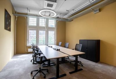 Modern office with yellow walls, adjustable desks, and large windows.