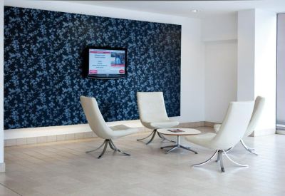 Communal lounge area featuring white swivel chairs and a blue floral feature wall.