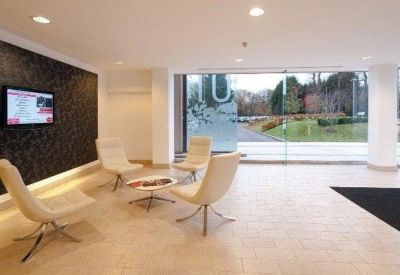 Bright reception lobby with white seating, floor-to-ceiling windows, and garden views.