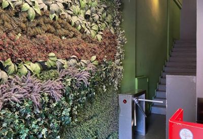 Office entrance hallway featuring a vibrant green living wall and security turnstiles.