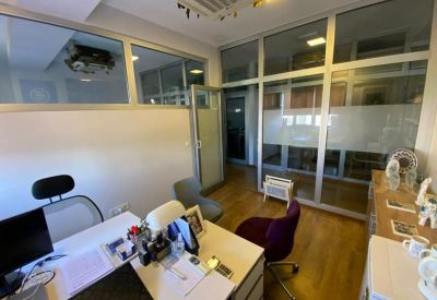Private office suite with a glass partition wall and modern white desk.